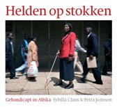 Vrouw in rode jas en zwarte rok, met witte stok in de hand, staand op trottoir.