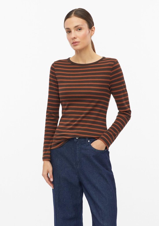 Model draagt een bruin-zwart gestreept aansluitend shirt met lange mouwen en een jeans.