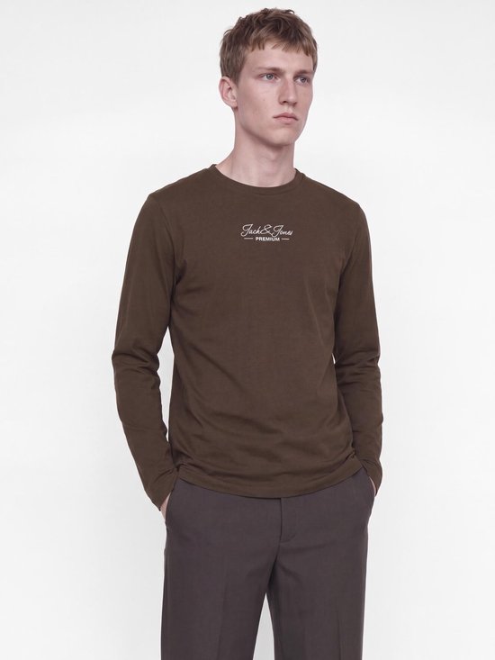 Model draagt een bruin shirt met lange mouwen en een wit Jack & Jones Premium logo op de borst.