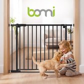 Zwart Bomi traphekje in een deuropening, met een peuter die met een puppy speelt in een woonkamer.