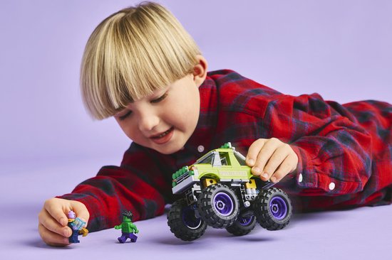 Jongen met groene LEGO monster truck, Hulk en paarse minifiguur.