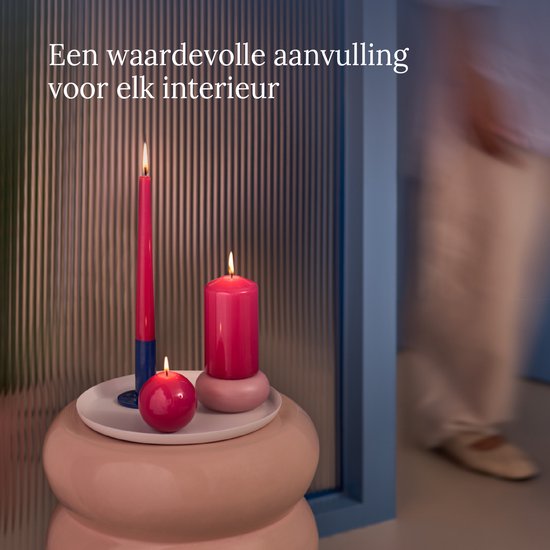 Twee fuchsia roze stompkaarsen, één hoog en één laag, en een bolkaars.