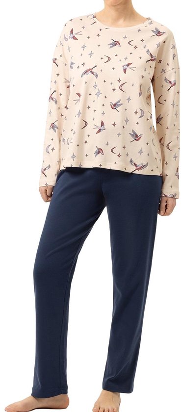 Model met lange mouwen pyjamaset in crème met vogels, sterren en manen print, met marineblauwe broek.
