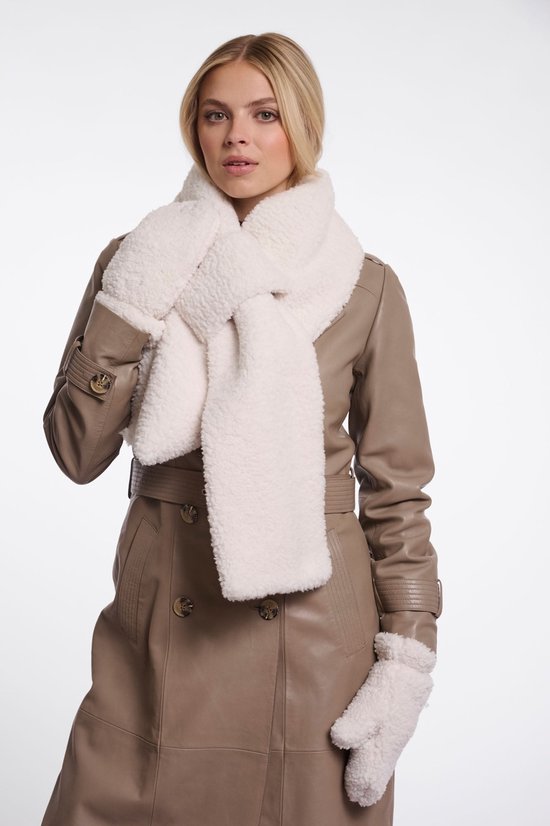 Model met blond haar draagt een beige leren trenchcoat, een witte pluizige sjaal en witte wanten.