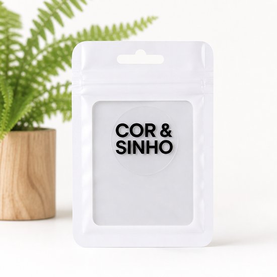 Witte verpakking met de tekst 'COR & SINHO' erop, naast een groene plant.