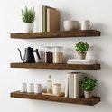 Drie rustieke, donkerbruine zwevende planken tegen een witte muur, gevuld met kookgerei, boeken en planten.