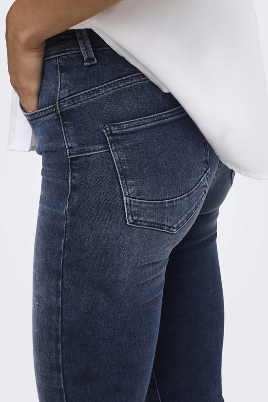 Detail van de achterkant van de blauwe jeans met push-up zakken en wit overhemd.