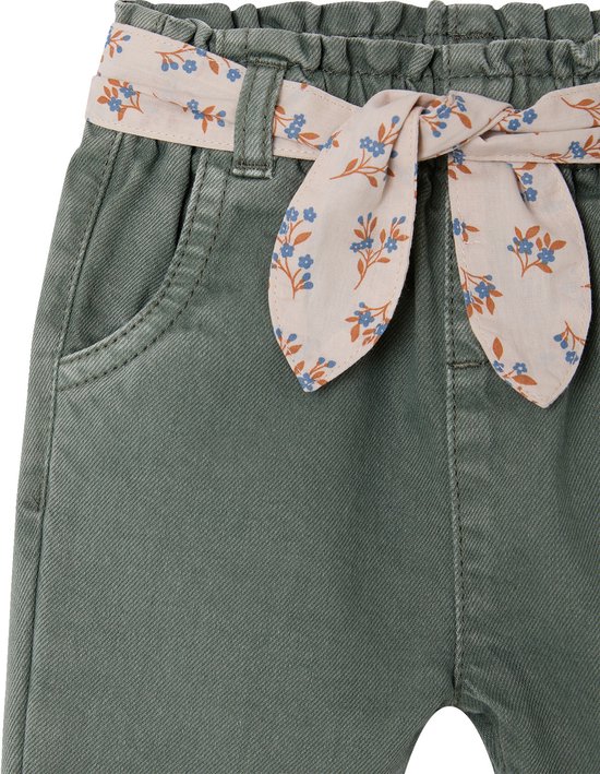 Detail van de tailleband van een olijfgroene broek met een gestrikte bloemige riem in roze.