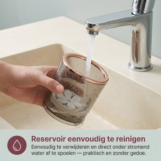 Transparante donkergrijze beker met koperkleurige rand, gevuld met water en een bloemvormige draaiplaat, onder een kraan.