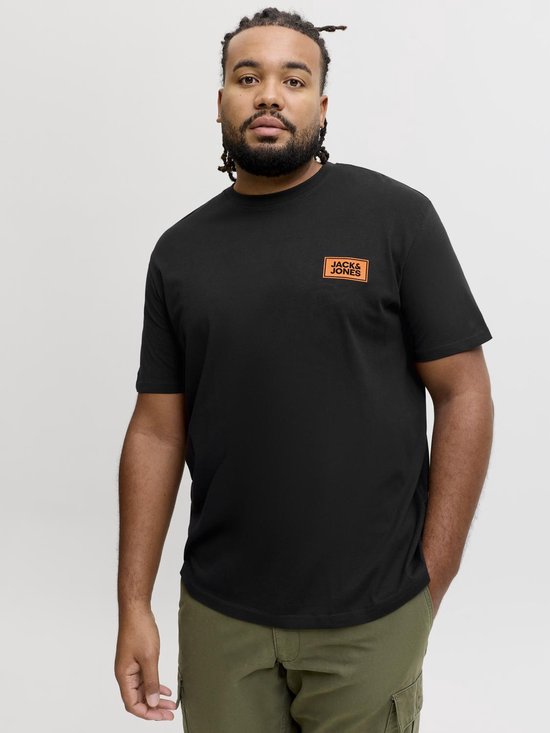Man met een donkere huidskleur, gekleed in een zwart T-shirt met oranje logo, en groene cargo broek.