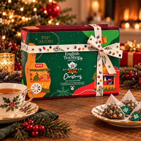 English Tea Shop geschenkdoos naast een theekopje en losse piramidezakjes op een houten tafel bij de kerstboom.