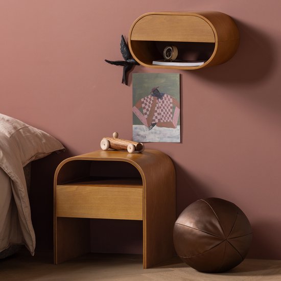Rond bruin houten nachtkastje met één lade, naast een bed en een houten speelgoedauto.