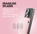 Roze powerbank magnetisch bevestigd aan achterkant van iPhone voor draadloos opladen.