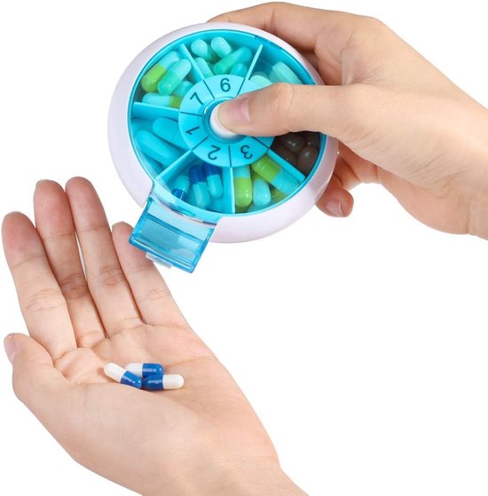 Handen vullen een ronde, witte pillendoos met turquoise compartimenten en kleine, gekleurde capsules.