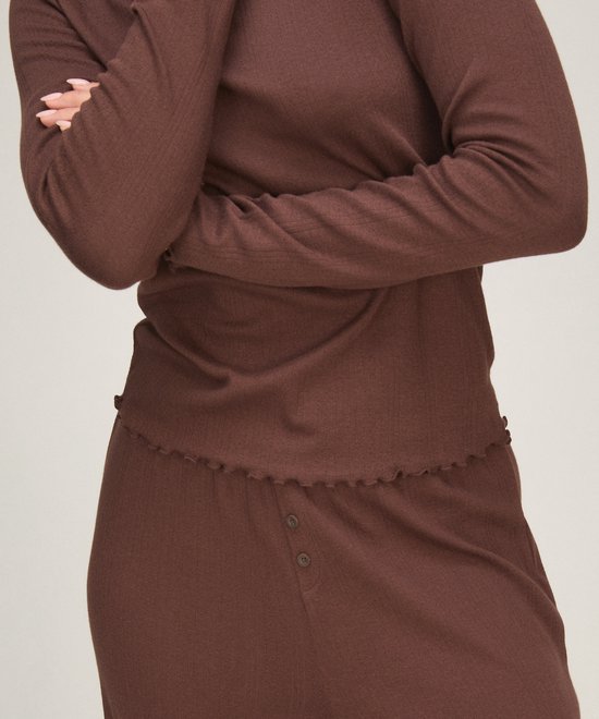 Close-up van een bruine pyjamaset met geribbelde textuur en geschulpte randen bij de taille.