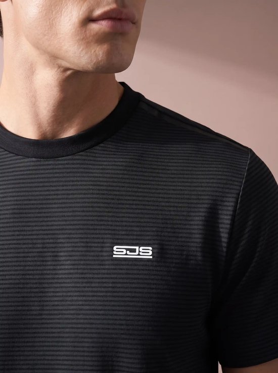 Close-up van een man in een zwart sportshirt met fijne horizontale strepen en het witte SJS-logo op de borst.
