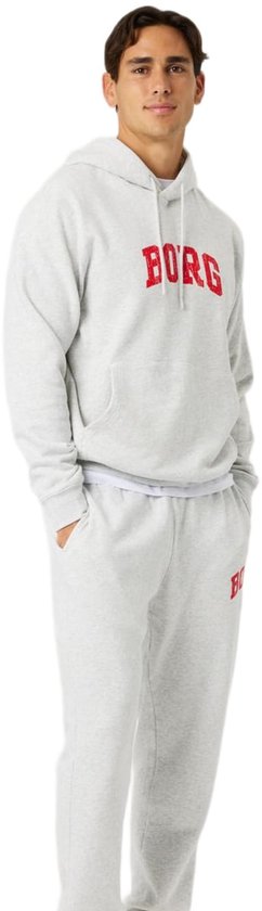 Lichtgrijze hoodie met rode 'BORG' tekst en joggingbroek, gedragen door een man met handen in de zakken.