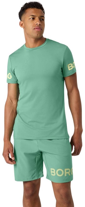 Man in lichtgroen sportshirt met korte mouwen en short, met gele tekst op de mouw en short.