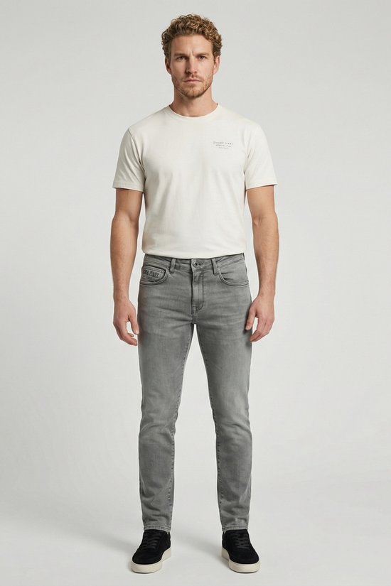 Man met lichtgrijze slim fit jeans en wit T-shirt.