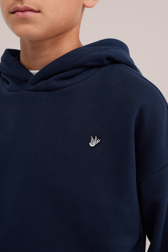 Close-up van een donkerblauwe hoodie met wit geborduurd vogel-logo op de borst.