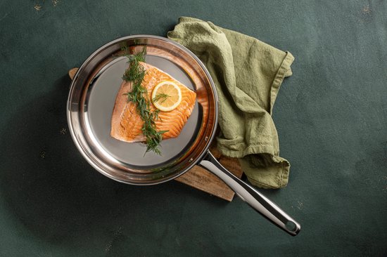 Zalmfilet met citroen en dille in een roestvrijstalen pan.