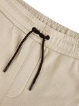 Detail van de elastische tailleband van de beige joggingbroek met zwart trekkoord.