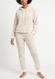Model draagt beige fleece loungewear met zebraprint. De set bestaat uit een hoodie met trekkoord en een joggingbroek.