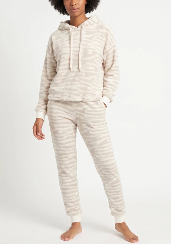 Model draagt beige fleece loungewear met zebraprint. De set bestaat uit een hoodie met trekkoord en een joggingbroek.