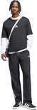 Man met zwarte Adidas sportbroek met witte strepen, zwart T-shirt met lange mouwen en een schoudertas.