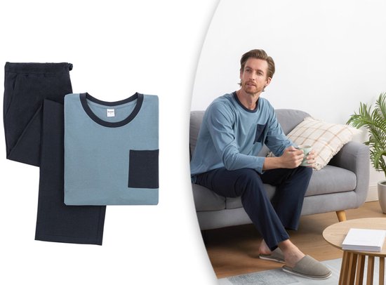 Man op bank in lichtblauw pyjamapak met donkerblauwe broek en zak. Naast pyjamaset.