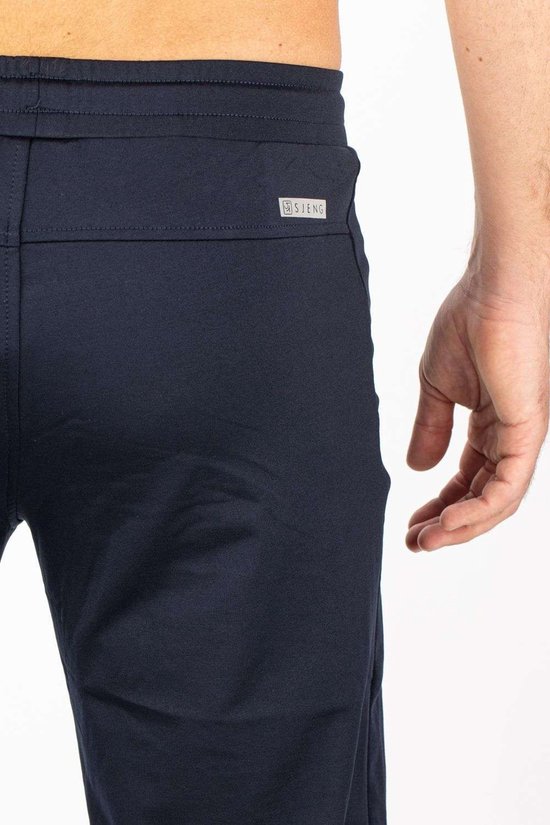 Donkerblauwe sportbroek met logo-badge van Sjeng Sports op de achterkant.