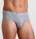Grijze herenslip gedragen door model, met elastische tailleband voorzien van het Sloggi-logo.