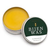 Rond metalen blikje met gele bijenwas, label met bijenlogo en tekst 'BIJENWAS - Van Nederlandse bijen'.