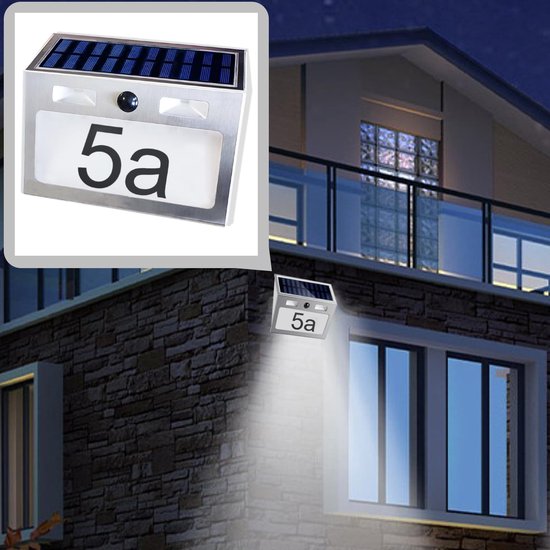 Huisnummer '5a' op zonne-energie gemonteerd aan een bakstenen gevel, verlicht het pad in de nacht.