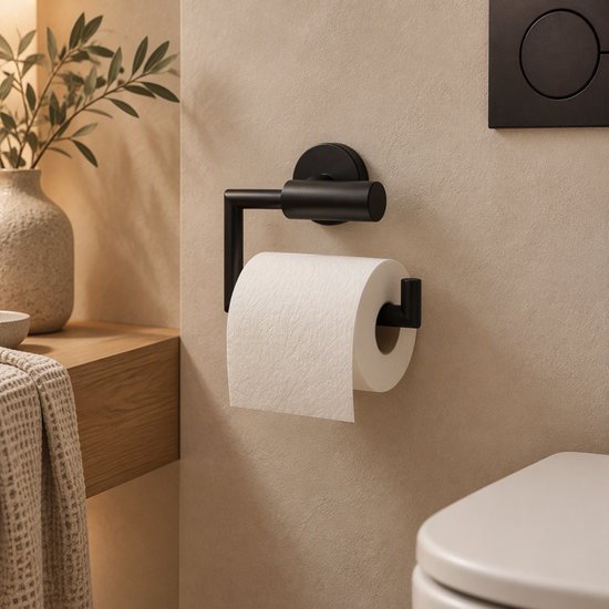 Matzwarte toiletrolhouder aan een beige wand in een sfeervolle badkamer.