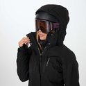Close-up van een vrouw die haar zwarte ski-jas sluit, met paarse skibril en helm.