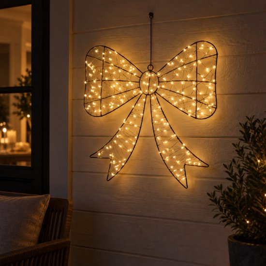 Grand nœud lumineux en fil métallique avec des centaines de petites lumières blanc chaud, accroché à l'extérieur sur un mur.