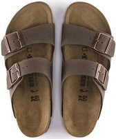 Bovenanzicht van bruine Birkenstock Arizona sandalen met koperkleurige gespen en kurken zool.