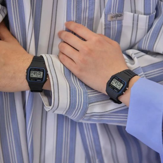 Deux personnes portant une montre Casio noire au poignet, vêtues d'une chemise à rayures bleues et blanches.