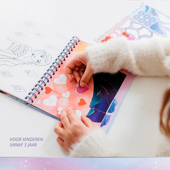 Enfant en gilet blanc collant des cœurs dans un livre La Reine des Neiges. Texte : Pour les enfants à partir de 3 ans.