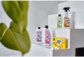 Assortiment Marcel's Green Soap schoonmaakmiddelen op witte treden, met deels onscherp groen blad op de voorgrond.