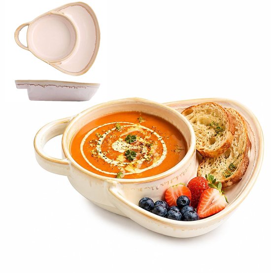 Beige keramische kom met tomatensoep, brood, aardbeien en blauwe bessen, inclusief een lege lege serveerschaal erboven.