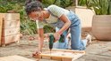 Vrouw met veiligheidsbril boort in een houten plank met de groene Bosch EasyDrill 18V-40.