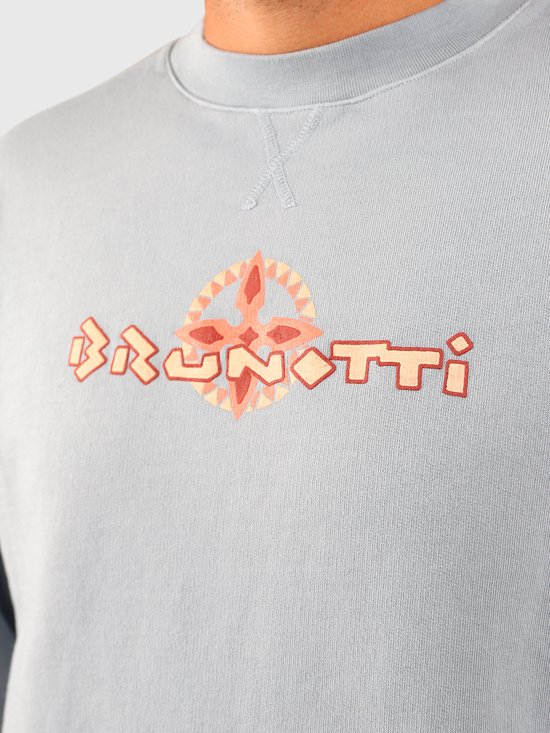 Close-up van een lichtblauwe sweater met het Brunotti logo en een gestileerd kompas in oranje tinten.