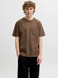 Model draagt een bruin t-shirt met borstzak en zwarte broek.