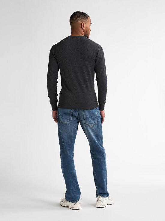 Model op de rug gezien, draagt een donkergrijze fijngebreide trui, blauwe jeans en witte sneakers.