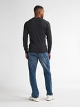 Model op de rug gezien, draagt een donkergrijze fijngebreide trui, blauwe jeans en witte sneakers.