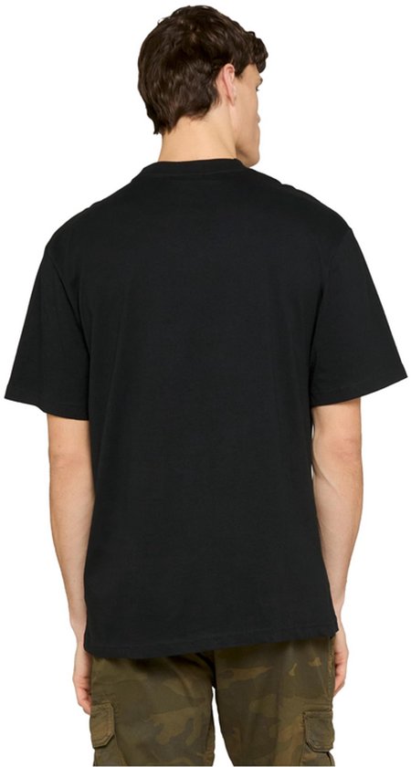 Achterkant van een zwart Urban Classics T-shirt gedragen door een man met camouflagebroek.
