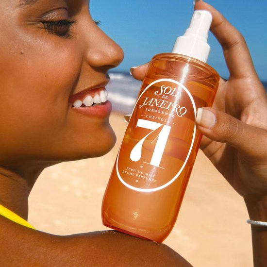 Vrouw met Sol de Janeiro Cheirosa '71 parfumnevel op een zonnig strand.