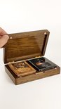 Hand opent een donkere eikenhouten koffer met twee spellen IVANKART kaarten: Wood Edition en Metal Edition.